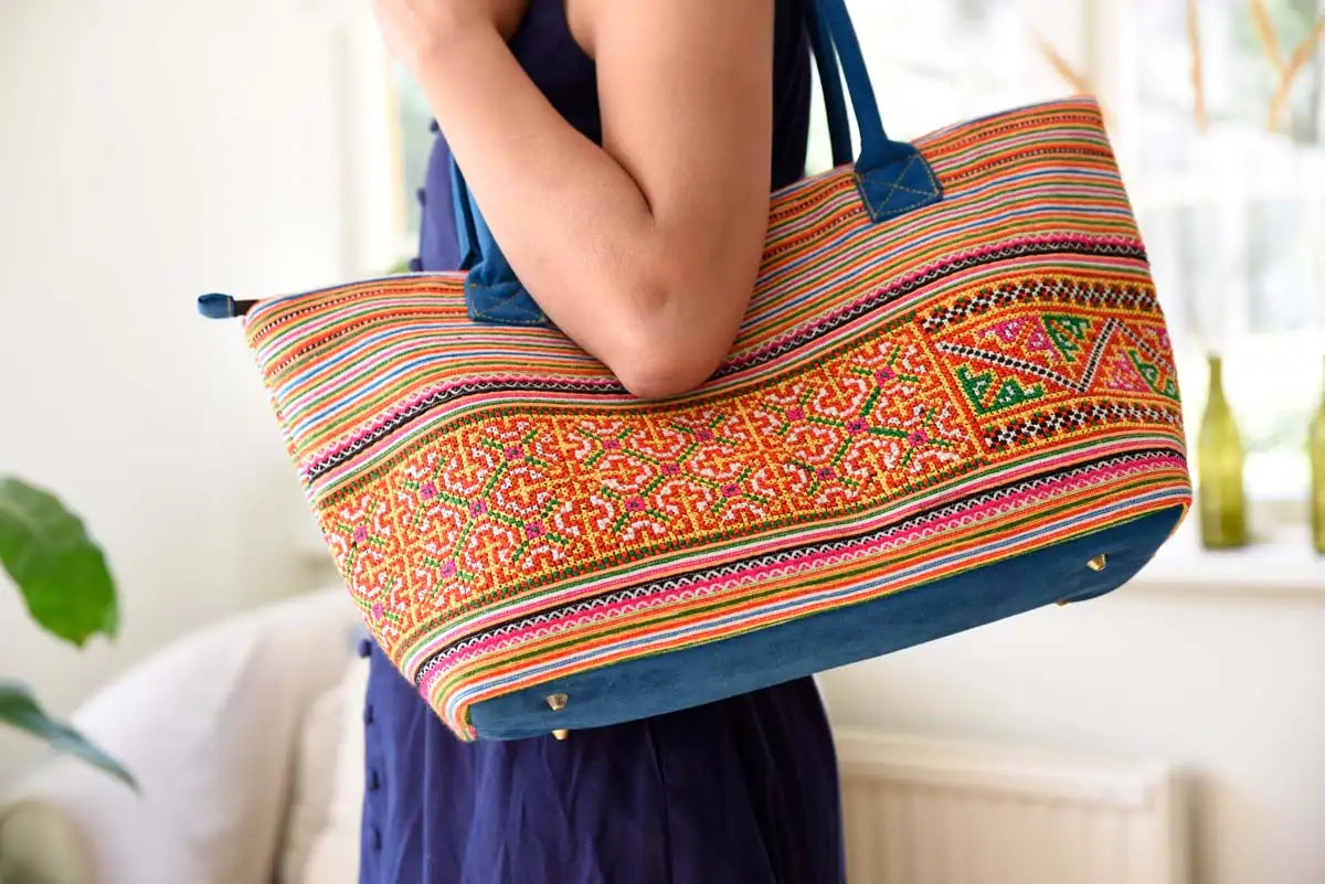 Vindigo tote bag made from orange tribal embroidered cotton fabric carried by model
