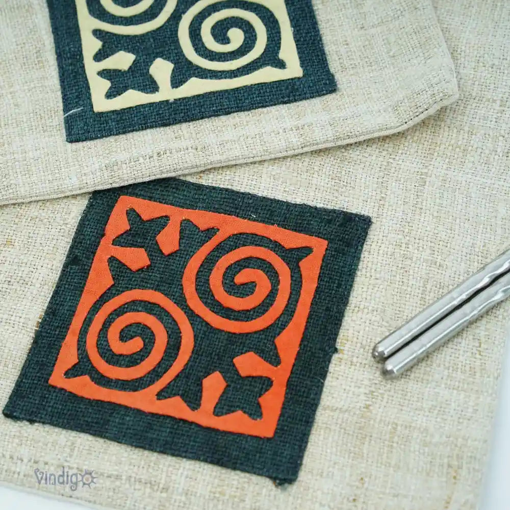 Detalj av orange och gröna tribaltryck på naturfärgat linne