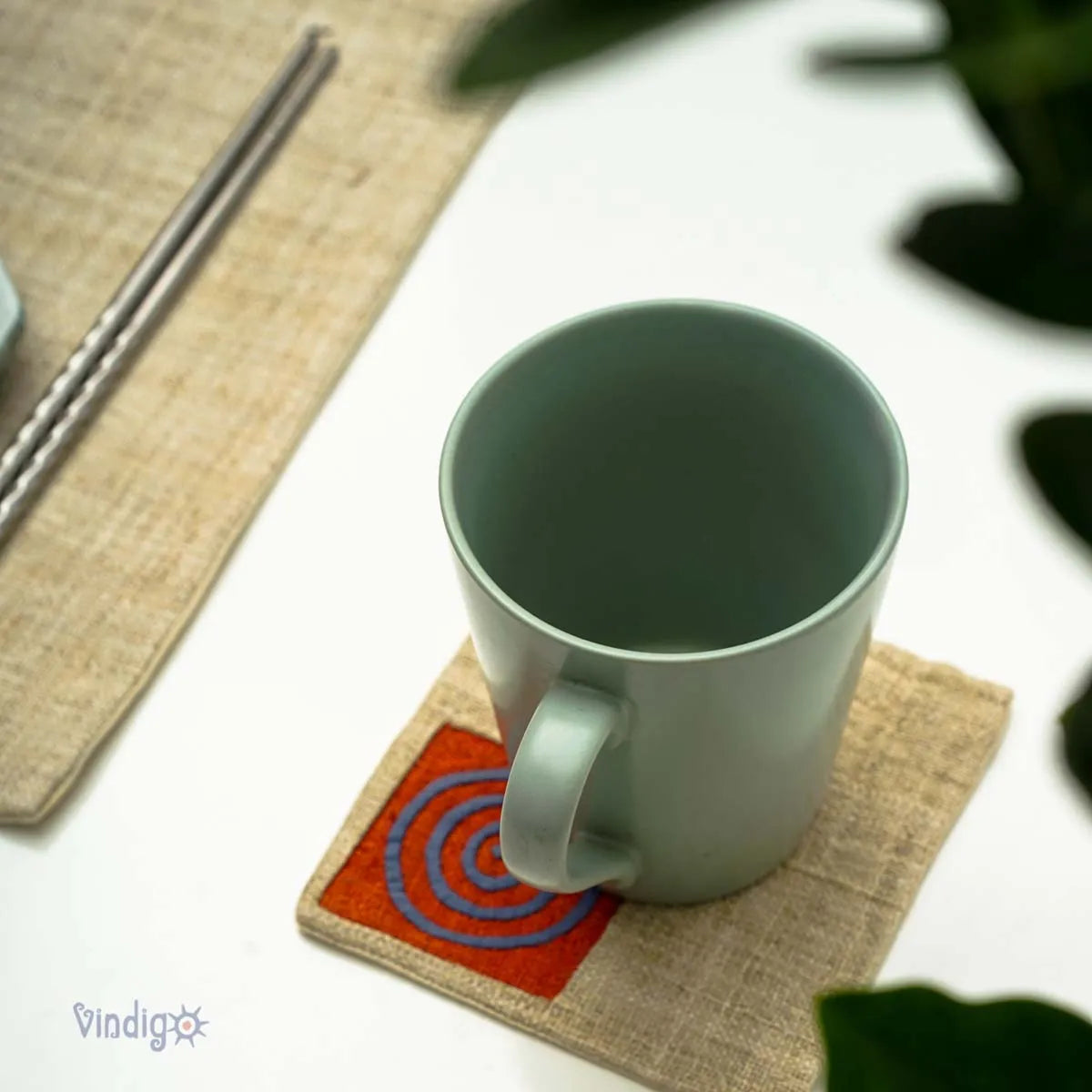 Närbild på kopp placerad på orange tribalunderlägg i linne