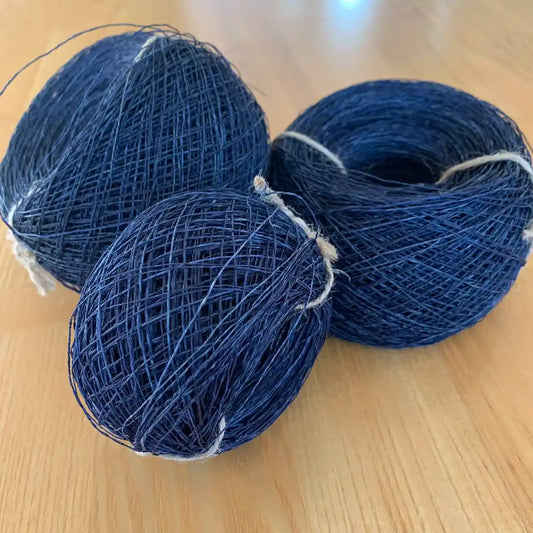 Tvinnade nystan av indigo färgat hampagarn på gräs.