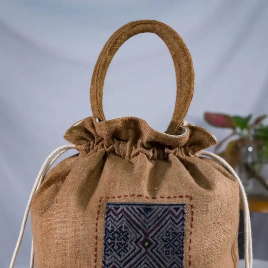 Angled view of natural hemp bucket bag with H’Mong patch and drawstring closure