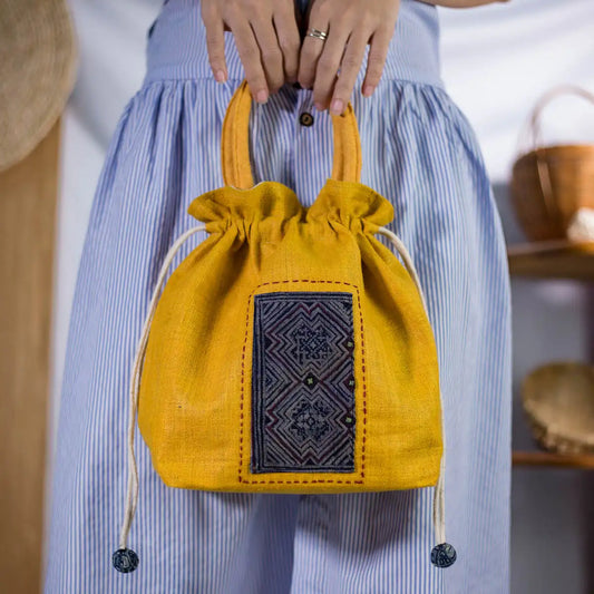Model carrying yellow hemp drawstring bucket bag by Vindigo, sustainable handmade handbag