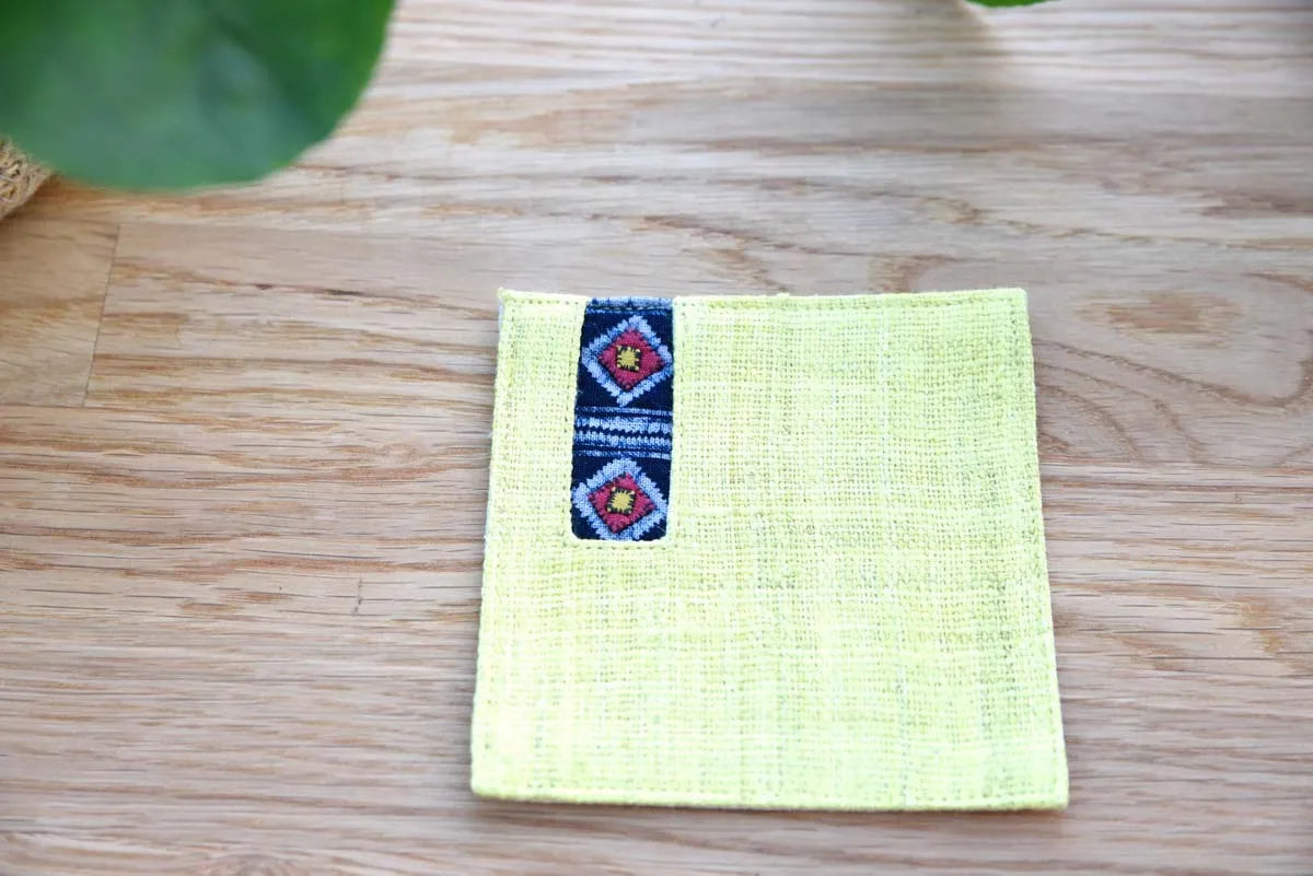 Front view of yellow hemp coaster with indigo embroidered stripe