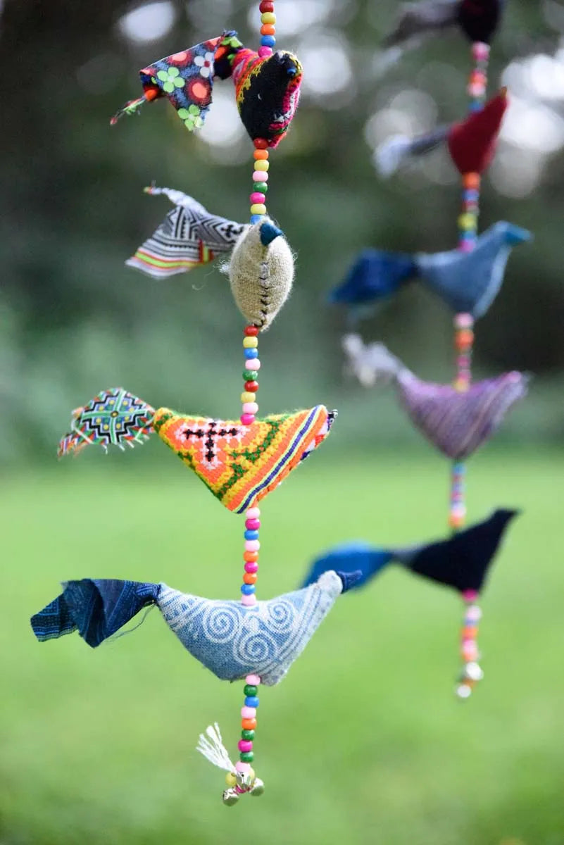 Närbild av hängande tygfåglar i flerfärgad bomull med pärlor