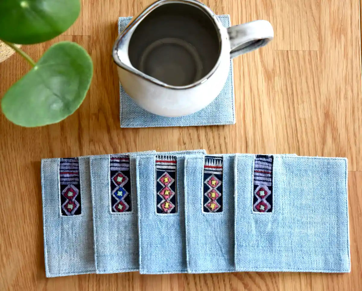 Light denim coasters styled with cup and greenery on wooden table