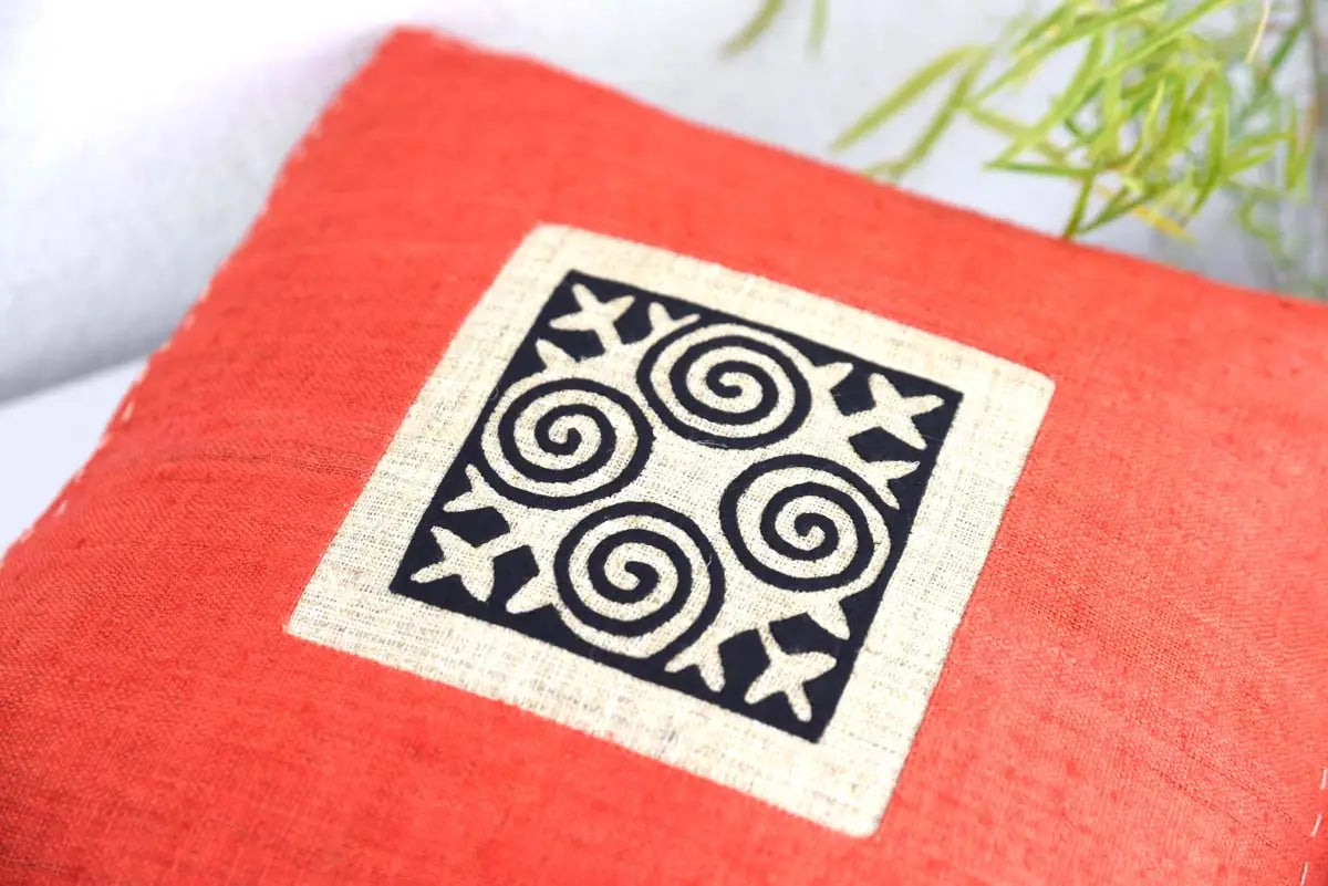 Närbild av kuddfodralets svarta tribaltryck på orange tyg