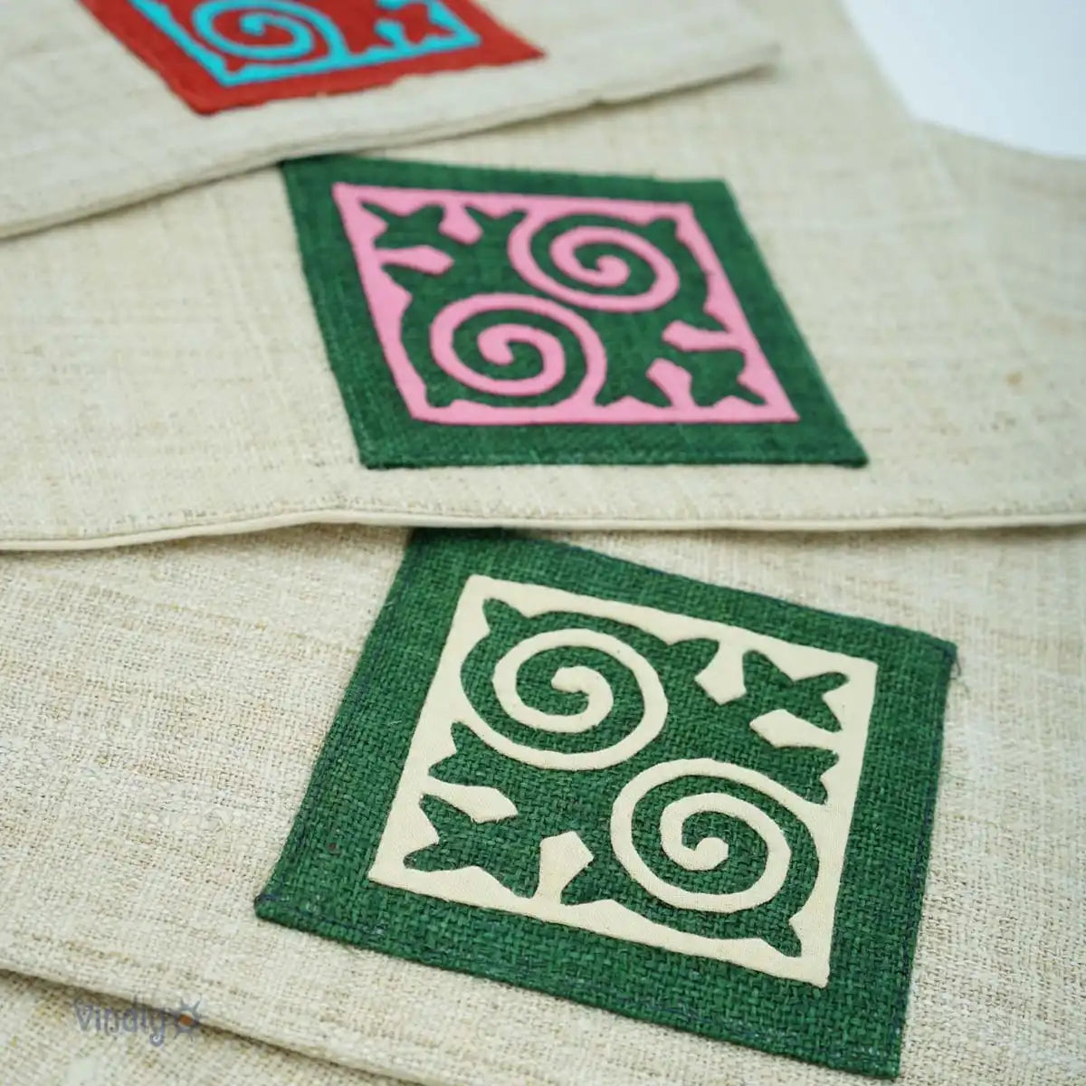 Närbild på linneservetter med handtryckta tribalrutor i rosa och grön
