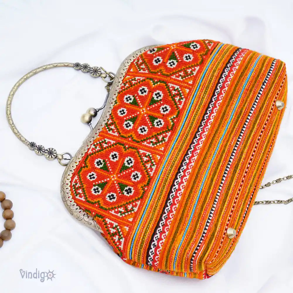 Närbild av orange tribaltyg med små broderade speglar och metallram