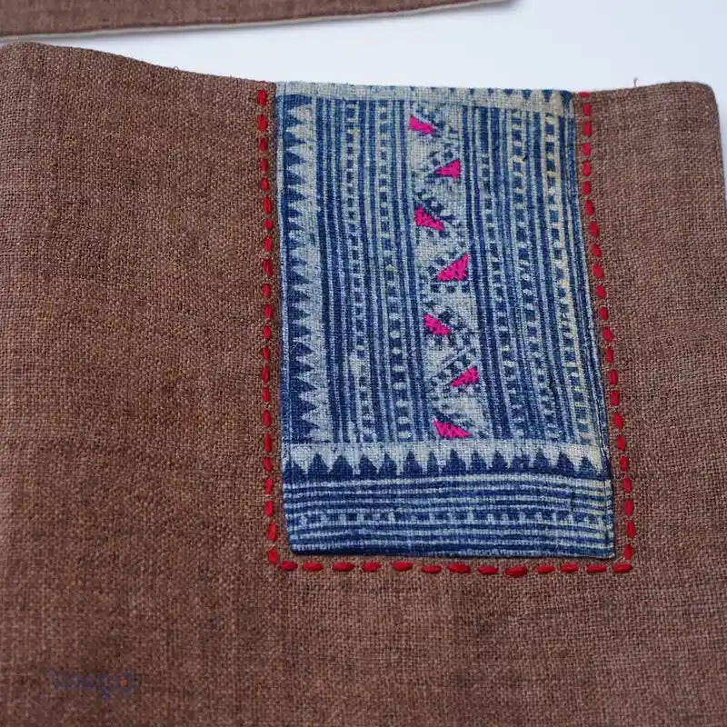 Närbild på blått handbroderat tribalmönster på brunt tygunderlägg