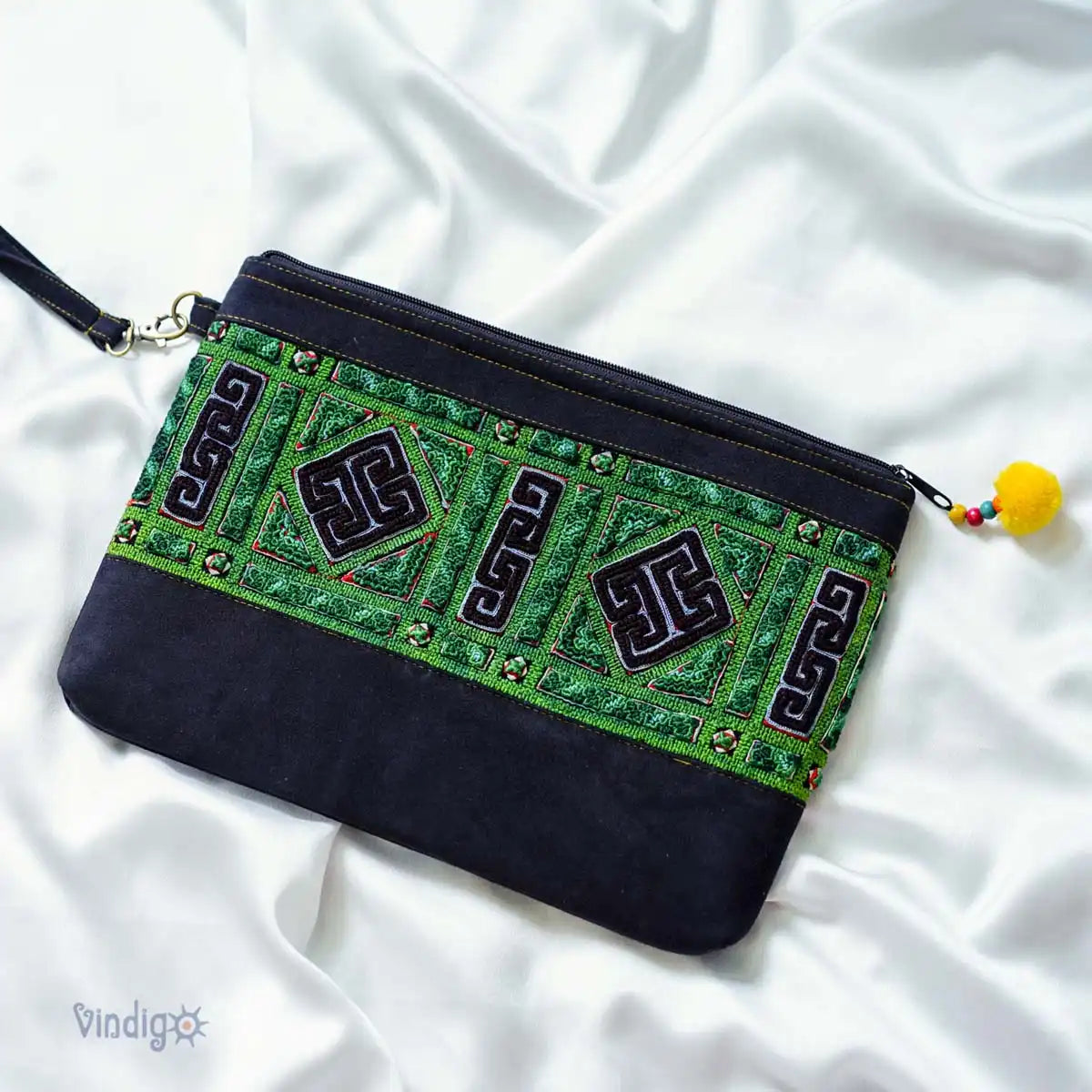 Flatlay of green and black tribal clutch bag on white fabric