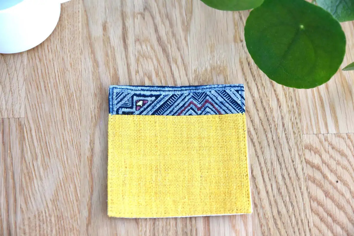 Yellow hemp coaster with indigo border placed on wooden table