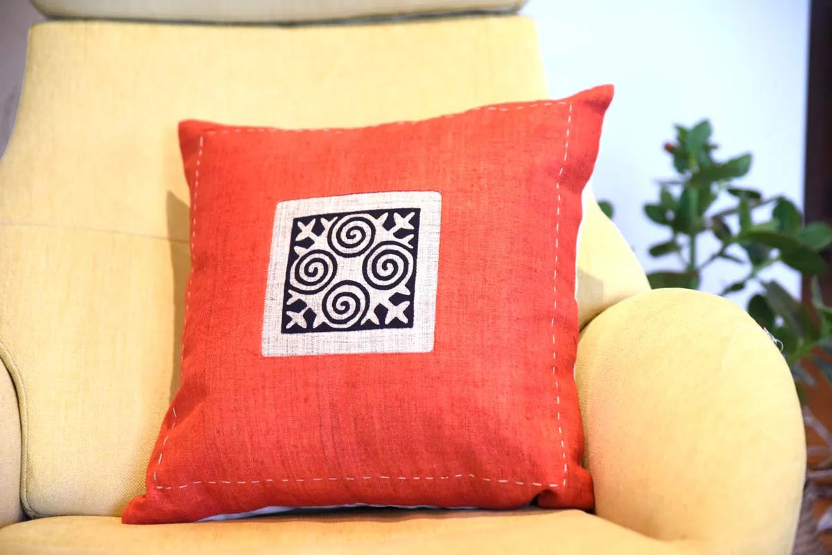 Orange kuddfodral med tribaltryck placerat i soffa med ljus bakgrund