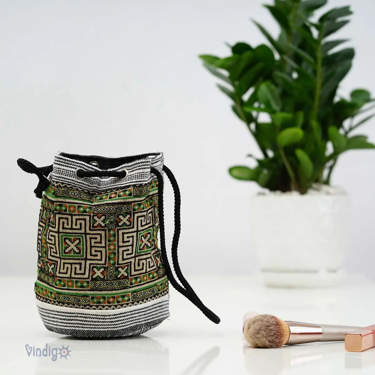 Handgjord grön hampaväska med tribalbroderi placerad bredvid växt i inredningsmiljö