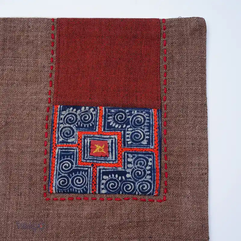 Detalj av handsydd tribalruta i blått och orange på linneunderlägg