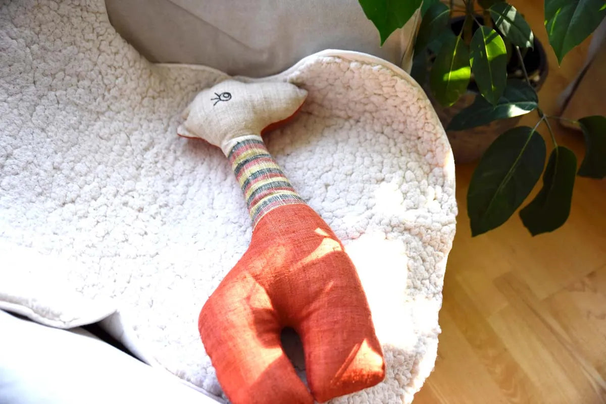 Vindigo orange stuffed deer resting on white blanket