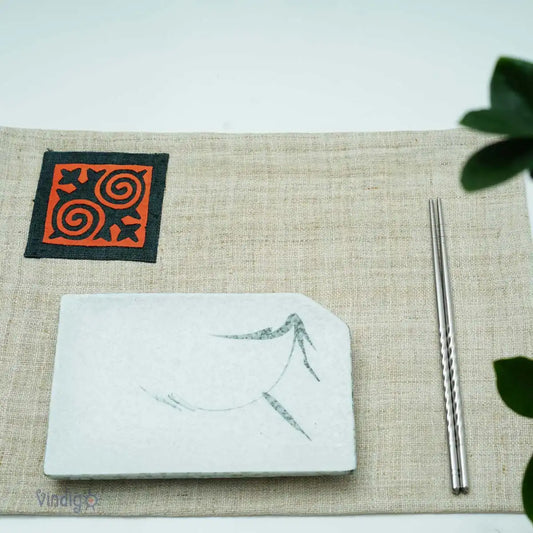 Linneservett med orange tribaltryck dukad på bord i ljus miljö