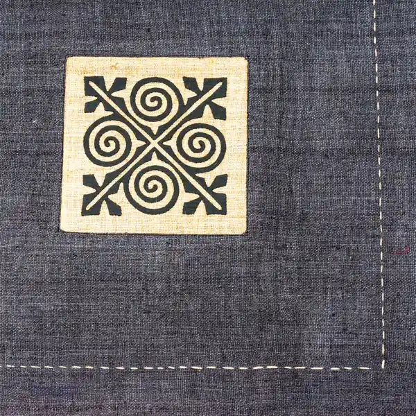 Närbild på svart tribaltryck med spiralformer på grå hampa