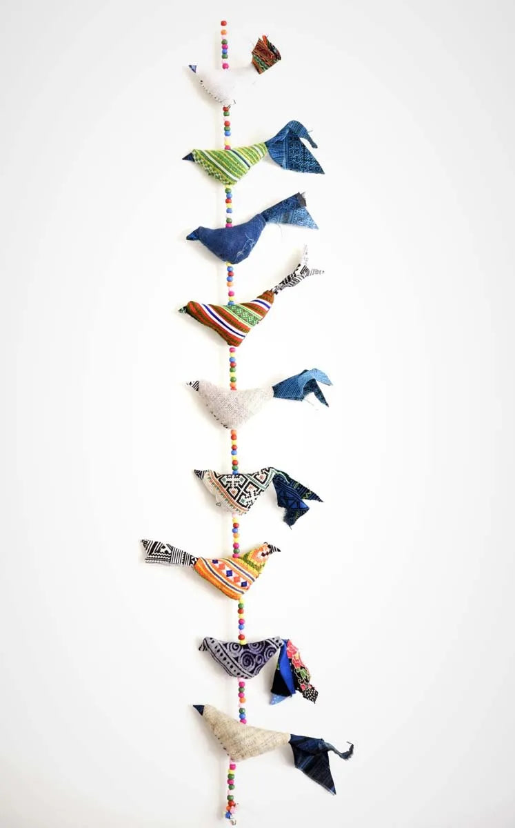 Vertikal dekoration med blå och gröna tygfåglar mot vit bakgrund