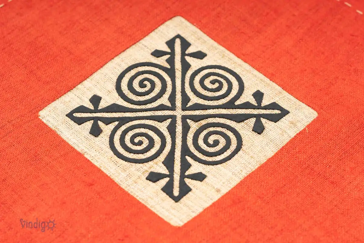 Detaljbild av svart geometriskt tribaltryck på orange kuddfodral