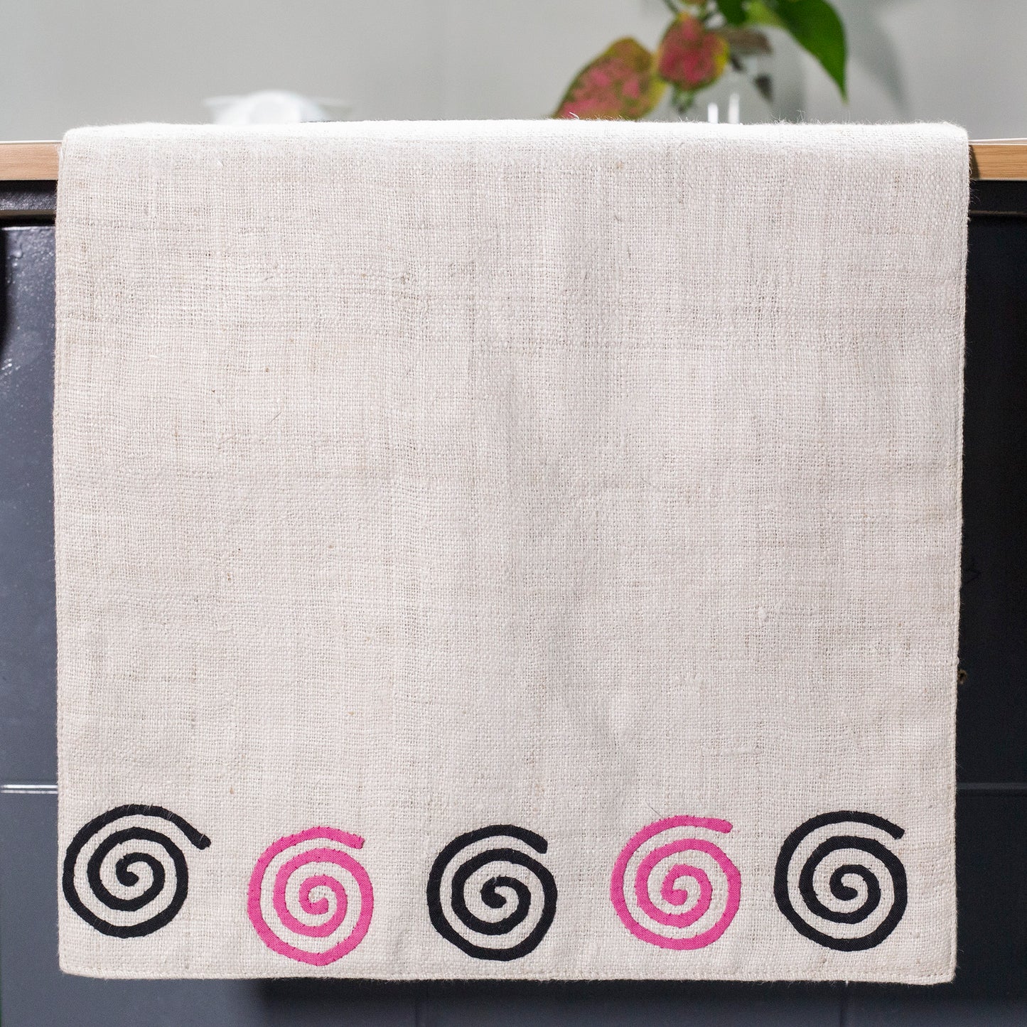 White Hemp Table Runner, white patch on black background, spiral patches in pink and black at two ends