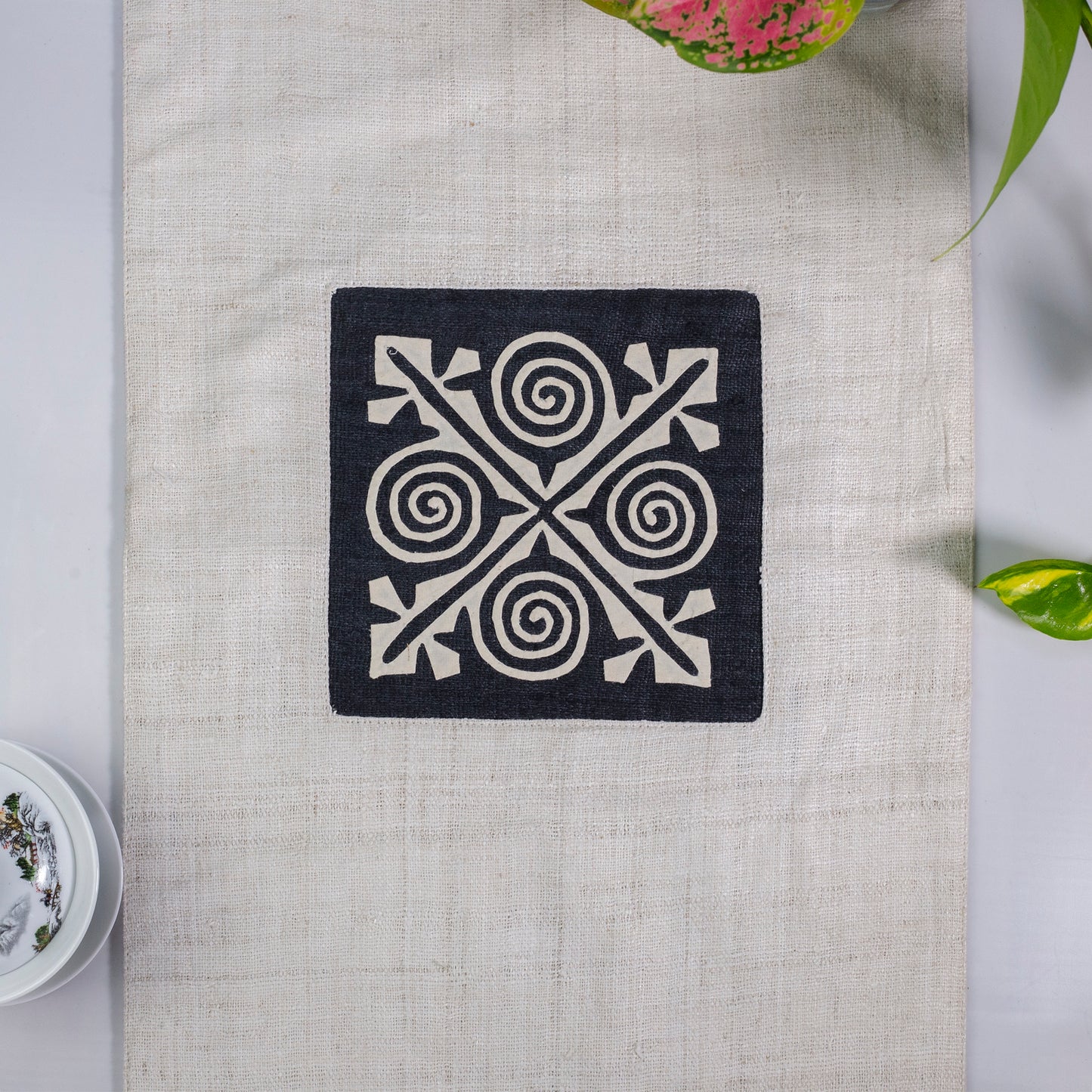 White Hemp Table Runner, white patch on black background, spiral patches in pink and black at two ends