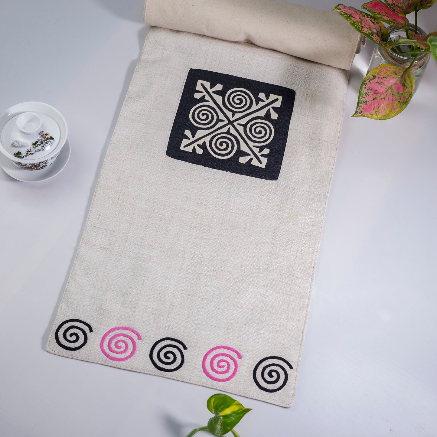 White Hemp Table Runner, white patch on black background, spiral patches in pink and black at two ends