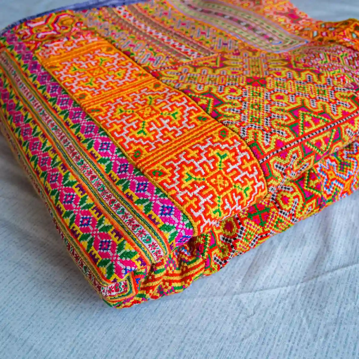 Vindigo orange Hmong batik and cross-stitched cotton bed cover folded view