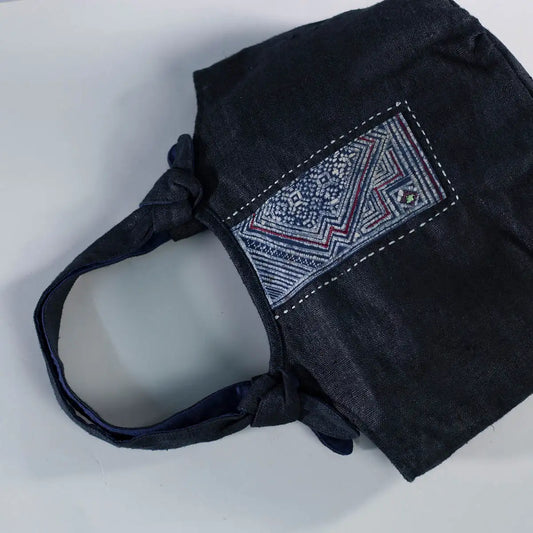 Angled view of black hemp bunny ear handbag with vintage H’Mong patch, sustainable handmade design