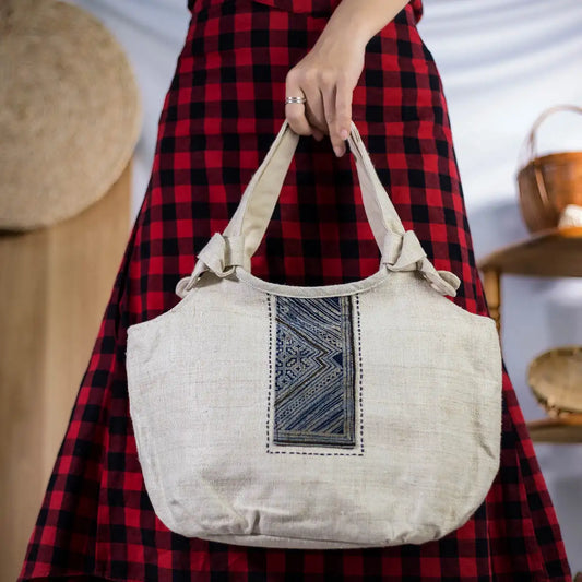 Model holding handmade hemp handbag with bamboo handle and H’Mong batik patch