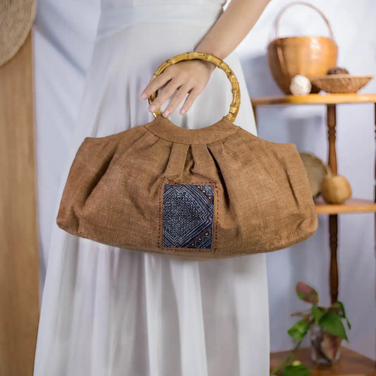 Model holding natural hemp bucket bag with bamboo handles and H’Mong patch, handmade fashion.